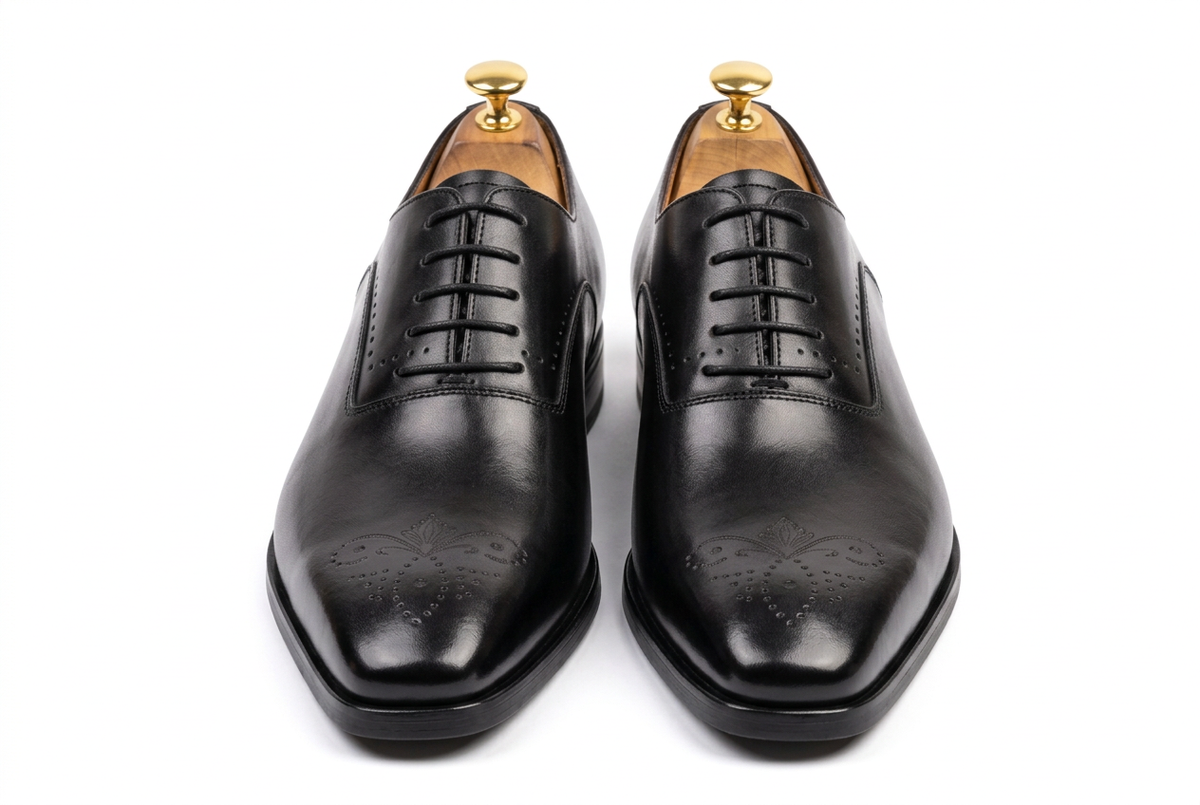 Chaussures noires légèrement vernies sur fond blanc, vue de face