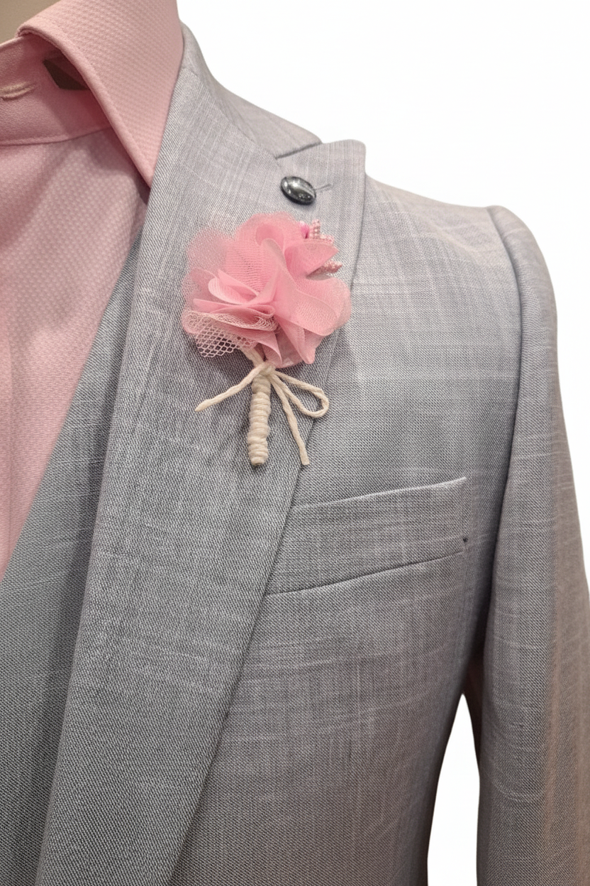 Détail boutonnière rose chiffon avec nœud blanc sur blazer gris clair
