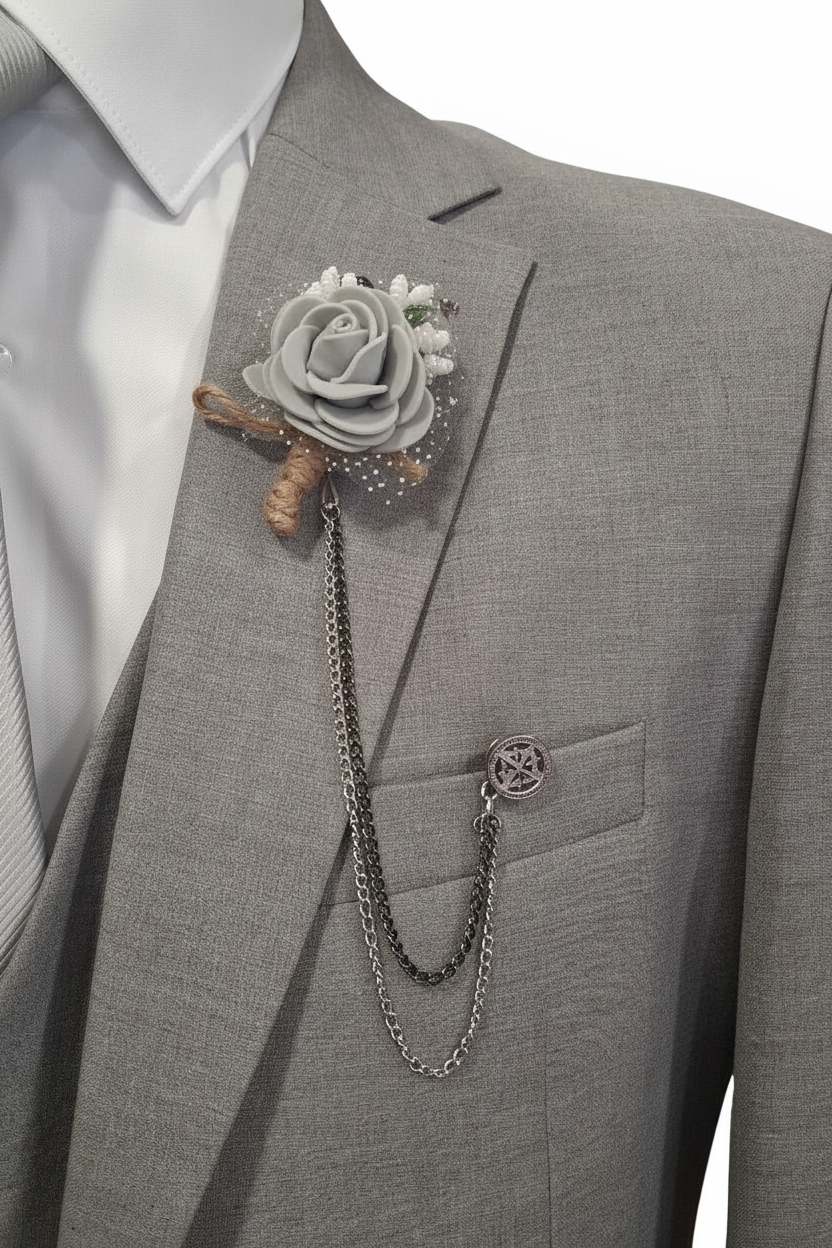 Détail boutonnière rose grise avec chaîne et médaillon boussole sur blazer gris