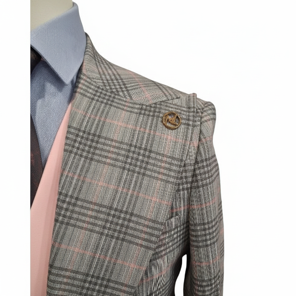 Gros plan détail broche ronde dorée laiton revers veste carreaux Prince de Galles gris beige lurex gilet rose chemise bleue fond blanc pur
