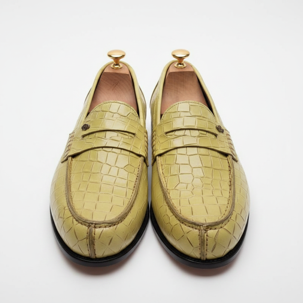 Mocassins penny loafer cuir croco embossé vert olive chartreuse vue frontale symétrique droite deux chaussures parallèles strap penny horizontal médaillon logo rose doré embauchoirs cèdre boutons dorés écailles croco face fond blanc pur studio luxe