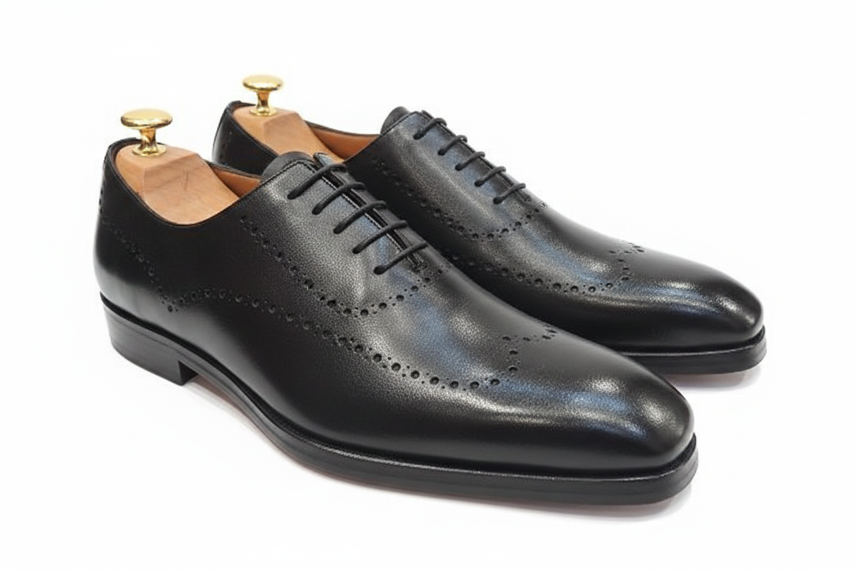 Oxford brogue noir double rangée perforations vamp complet embauchoir cèdre deux boutons dorés laiton vue large angle diagonal lacets noirs semelle cuir fond blanc pur studio luxe
