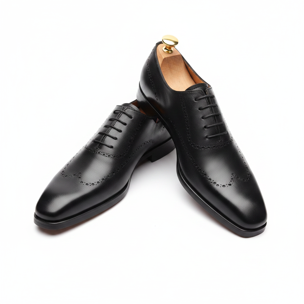 Oxford brogue noir vue plongeante avant légèrement élevée pointe carrée chisel lacets noirs vamp dessus embauchoir cèdre bouton doré grand rond proéminent perforations brogue bord fond blanc pur studio luxe