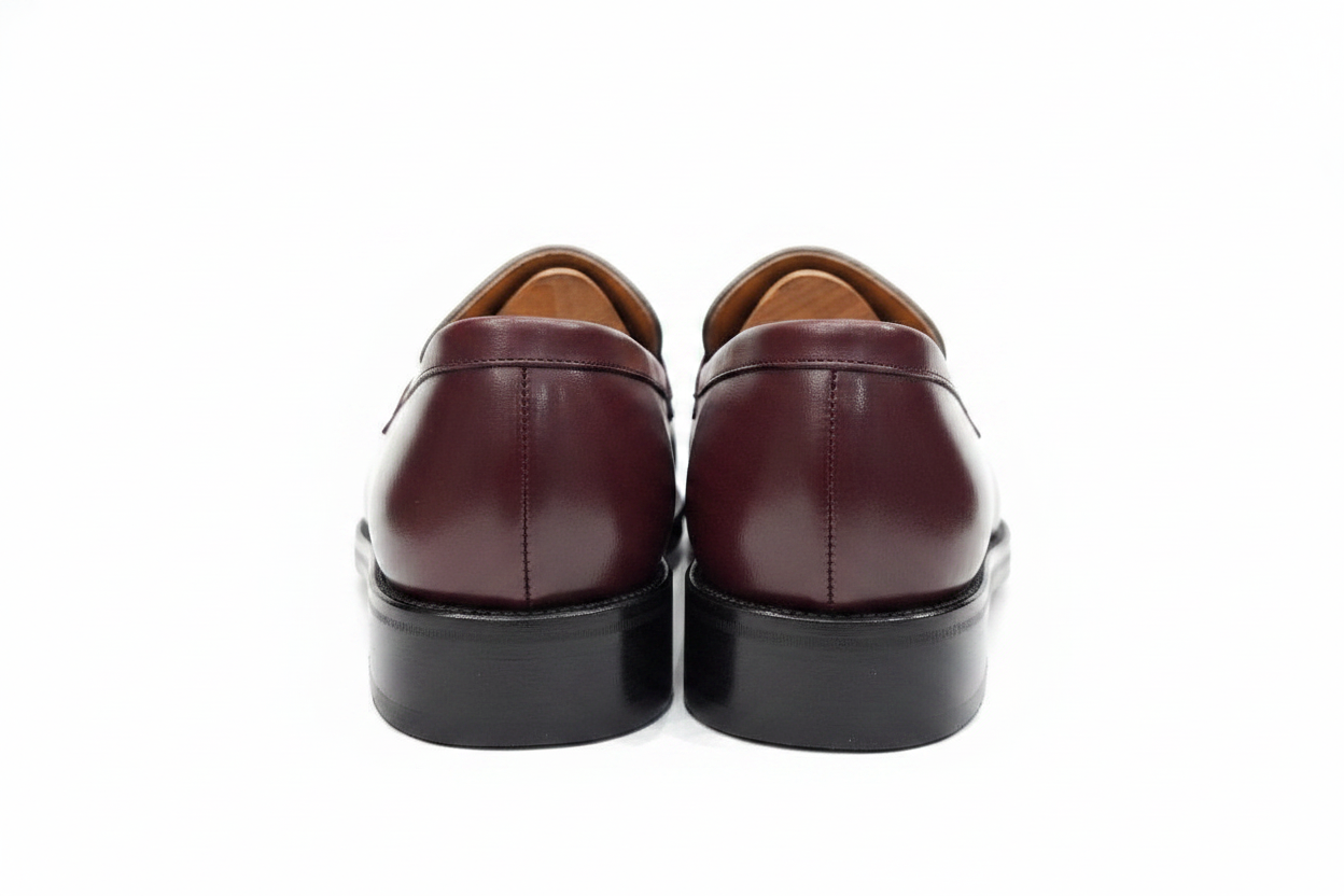 Paire de mocassins bordeaux blanc vue arrière rapprochée contreforts et talons empilés noirs sans embauchoirs sur fond blanc pur
