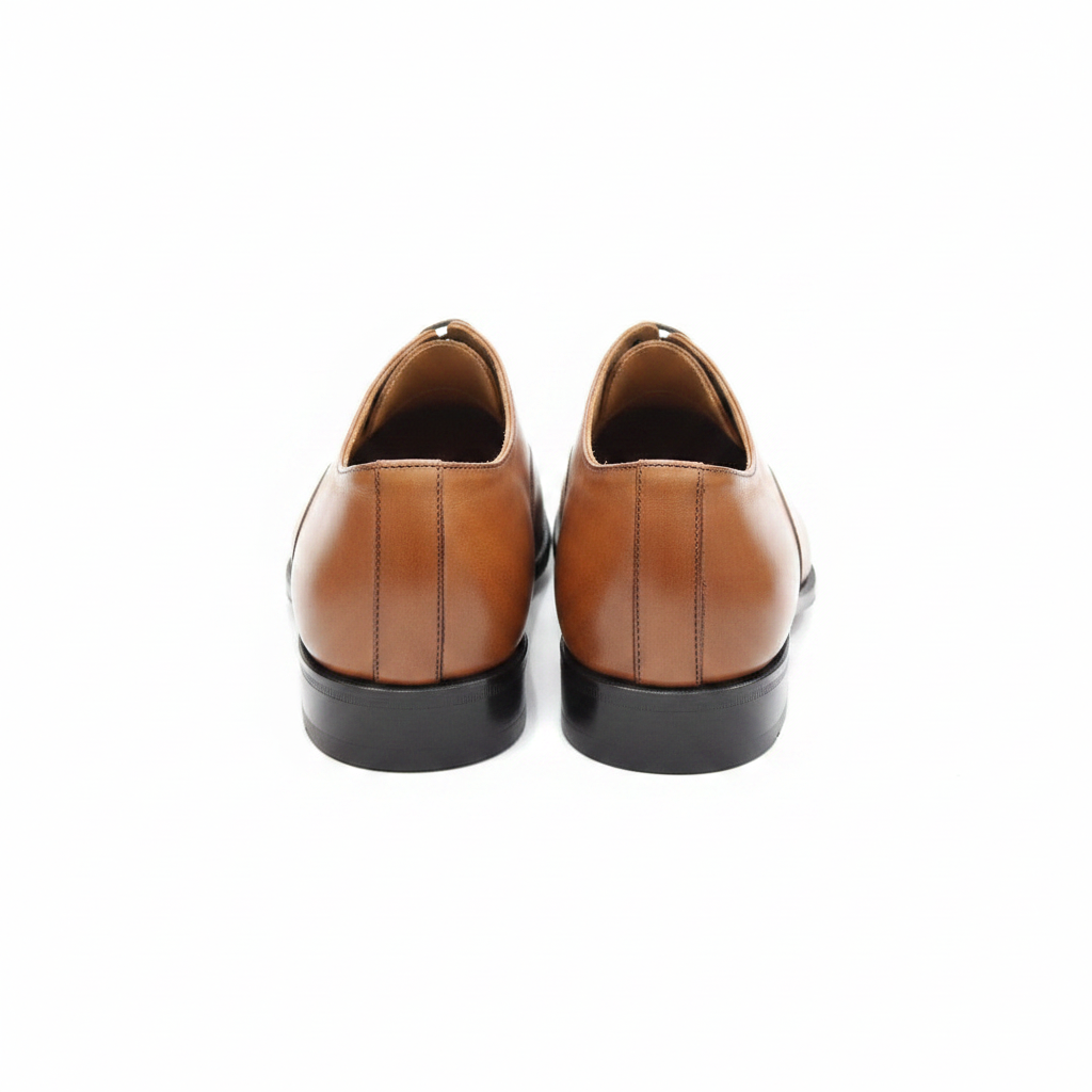 Richelieus marron cognac wholecut bout pointu vue arrière trois-quarts contreforts arrondis semelle noire fond blanc pur